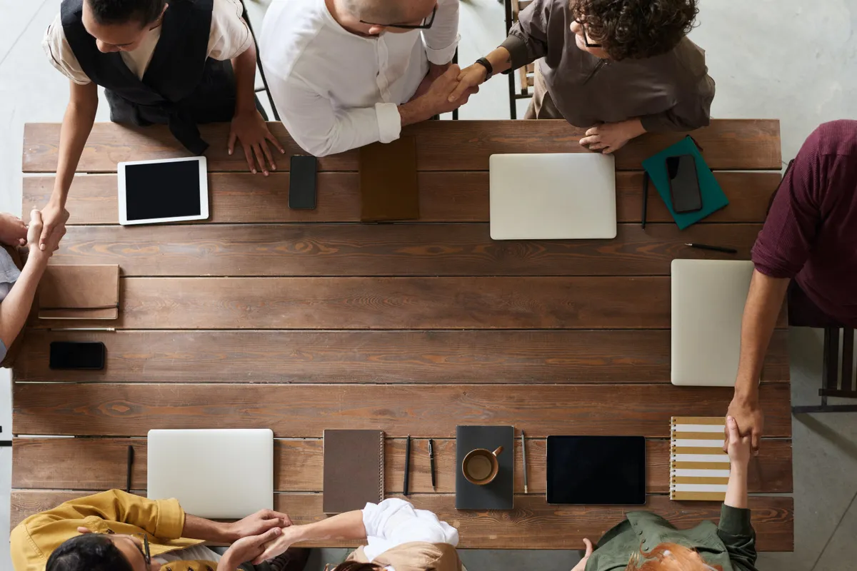 Top-down view of people shaking hands around a wooden table